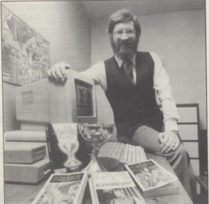 John Sweeney with his freshly won Holy Grail and the things he had to use to win it: his computer, his Lancelot game, and lots and lots of reference books.